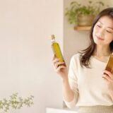えごま油と亜麻仁油の瓶を両手に持ち、どちらにしようか見比べる女性