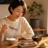 週に一度ほど魚を食べる日、焼き魚の定食を前に静かに向き合う女性