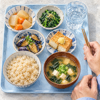 牛乳をやめてお腹の調子が良くなった、玄米ごはんとわかめのみそ汁に野菜のおかずが並ぶヴィーガン(ビーガン)の昼ごはんを真上から描いた水彩イラスト