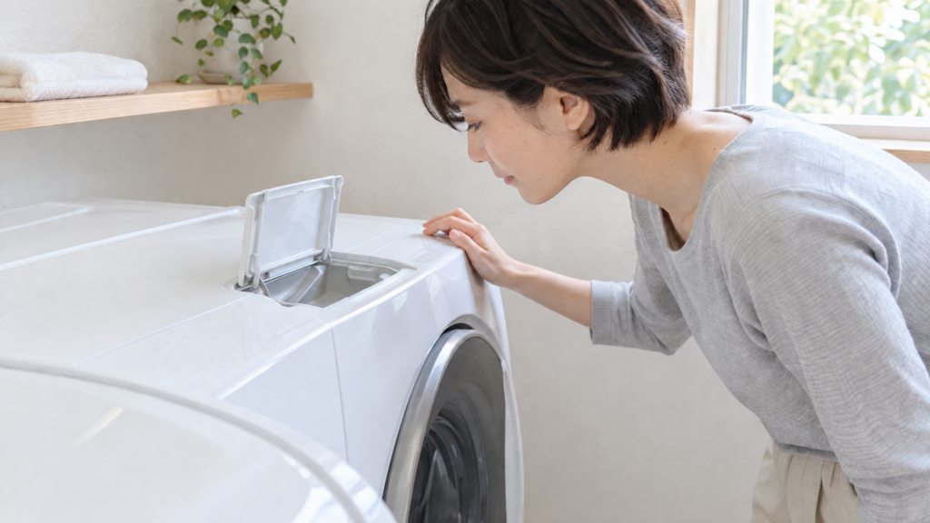 海へ…洗剤は洗濯機の自動投入機能に使えない。自動投入タンクのふたを開けて確かめる女性