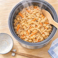 切り干し大根の戻し汁は炊き込みご飯にも使える。炊き上がった切り干し大根と大豆とにんじんの炊き込みご飯を炊飯器の内釜ごと上から見た水彩イラスト