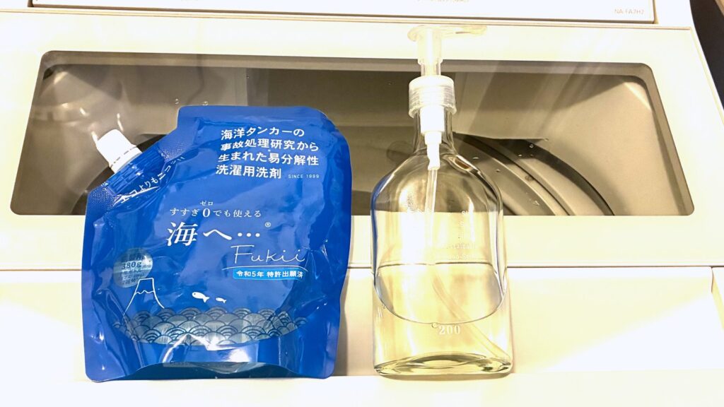 海へ…洗剤の詰替パック380gと、我が家が3年使っているポンプ式のガラスボトル。縦型洗濯機のふたの上に並べたところ