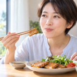 テンペはまずい?甘辛いタレで焼いたテンペをひと口食べて、思ったよりおいしいと笑顔になる日本人女性