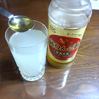 薄くなった2回目のこうじ水は、200mlにりんご酢小さじ1。グラスのこうじ水にスプーンでりんご酢を入れるところ